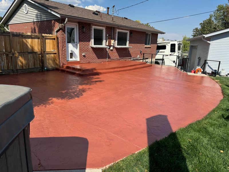 Terracotta integrally coloured concrete patio wrapping the back of a brick ranch