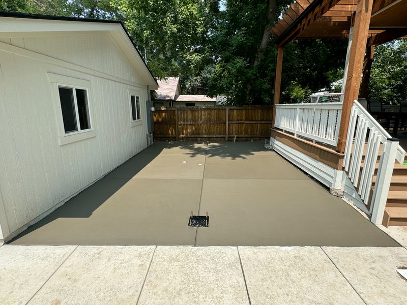 Freshly poured concrete patio slab beside a detached garage with the forms still in place