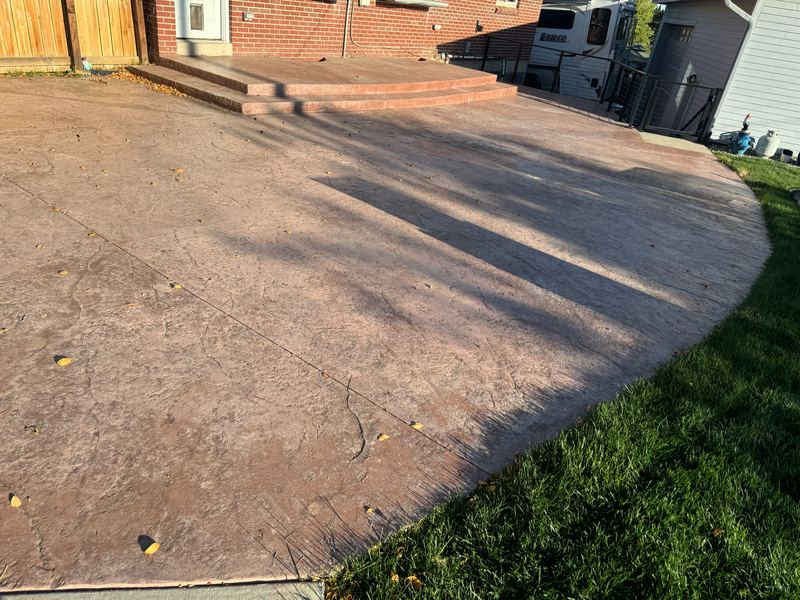Tan stamped concrete patio with a curved edge and a stepped landing