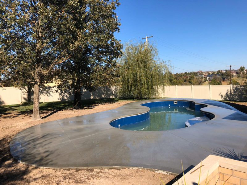 New concrete pool deck poured to the curve of a freeform pool