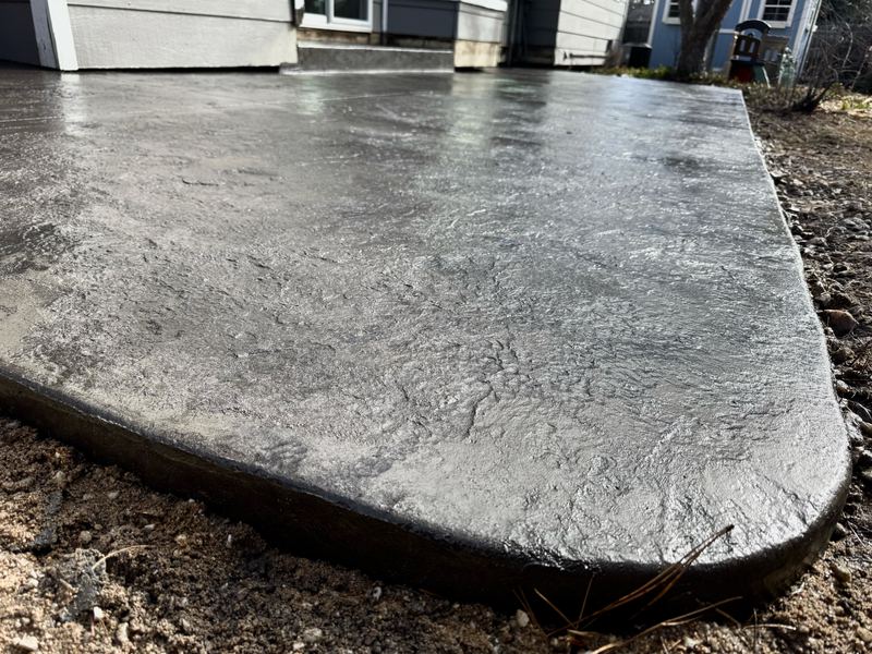 Close-up of a rounded stamped concrete edge showing the slate texture and joint line