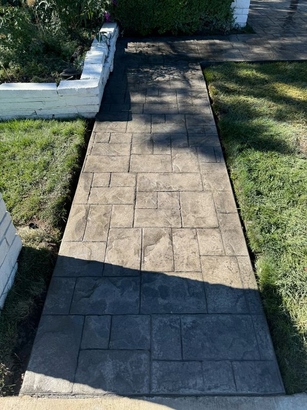 Stamped concrete walkway in a grey and charcoal ashlar pattern leading to a side gate