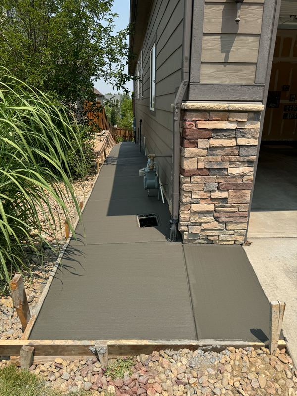 New concrete walkway poured along a house past a stone-clad column